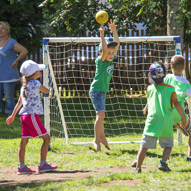 Kinder spielen Fußball im Garten der KiTa Eurasburg.
